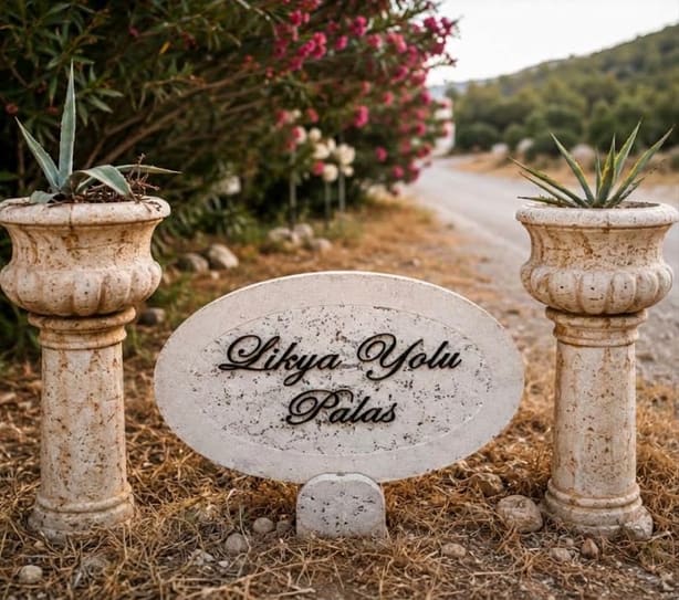 The stone entrance sign for Likya Yolu Palas, set among the garden greenery
